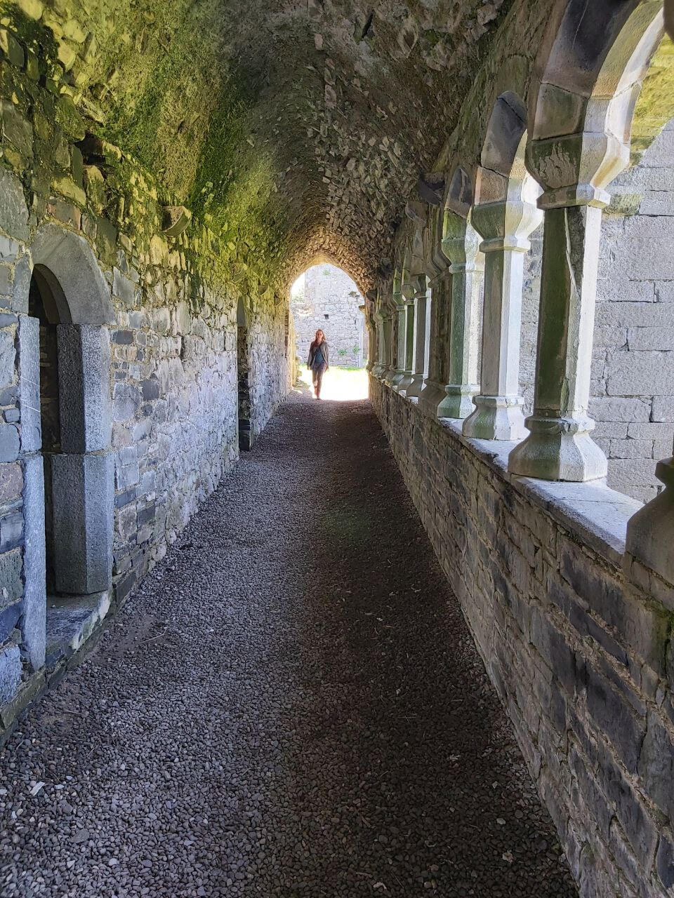 A woman walking through a medieval courtyard, as part of a female rites of passage experience in Ireland