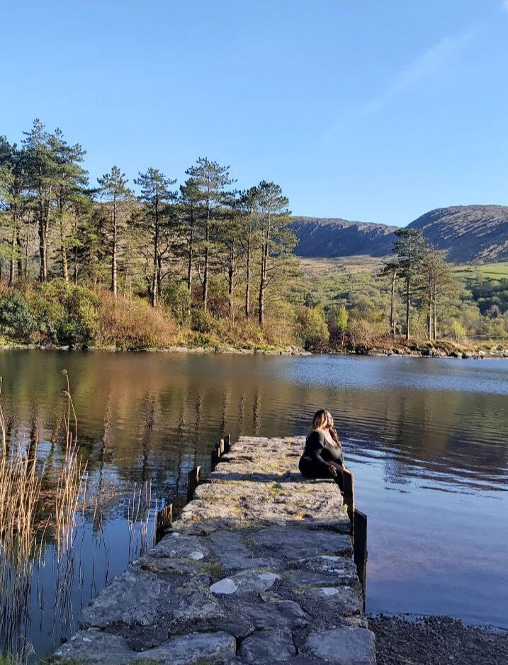 A woman looking out from a jetty over a silent Irish lake, finding nature-based inspiration on how to change your life